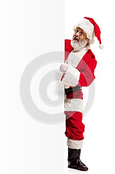 Happy Santa Claus pointing on blank advertisement banner background with copy space. Smiling Santa Claus pointing in