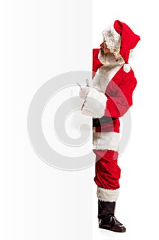 Happy Santa Claus pointing on blank advertisement banner background with copy space. Smiling Santa Claus pointing in