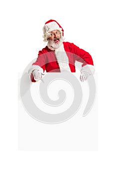 Happy Santa Claus pointing on blank advertisement banner background with copy space. Smiling Santa Claus pointing in