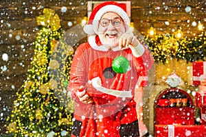 Happy Santa dressed in winter clothing think about Christmas near Christmas tree. Theme Christmas holidays and winter