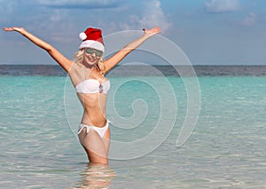 Happy Santa Girl on Tropical Beach. Beautiful blonde young woman