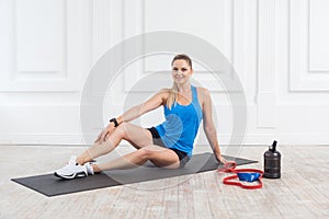 Happy satisfied beautiful young athletic causcasian woman in black shorts and blue top siting and have a rest after hard working