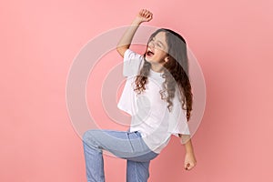 Happy satisfied little girl showing yes gesture and screaming celebrating her victory.