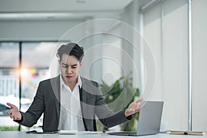 Happy satisfied millennial man using laptop at office workplace, working from home, reading message with good news