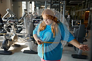 Happy satisfied overweight woman seeing good result on measuring tape