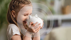 Happy savings. Close-up, little cute girl with white piggy Bank in her hands