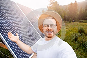 Happy Scandinavian man in hat and glasses takes selfie photo background of solar panels. Concept friendly technology for