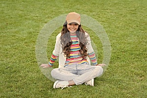 Happy school age girl child smile sitting on green grass, kid