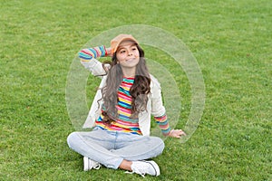 Happy school age girl kid smile sitting on green grass, child