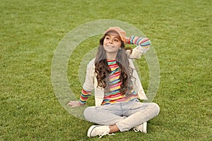 Happy school age girl kid smile sitting on green grass, child