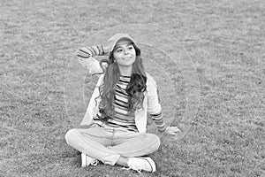 Happy school age girl kid smile sitting on green grass, child