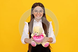 Happy school age kid hold teddy bear with love you heart yellow background, Valentines gift