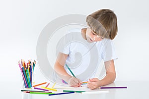 Happy school boy paiting at a white desk