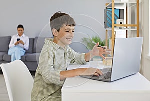 Happy school child having fun and using his laptop computer for online education