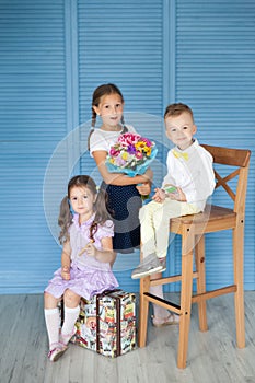 Happy school children in a uniforn with big gingerbread pencils and bouquet of autumn flowers