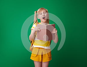 Happy school girl with book yawing isolated on green photo