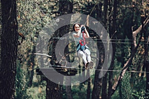 Happy school girl enjoying activity in a climbing adventure park