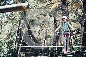 Happy school girl enjoying activity in a climbing adventure park