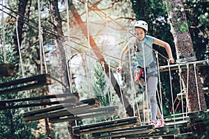 Happy school girl enjoying activity in a climbing adventure park