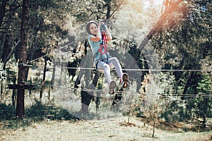 Happy school girl enjoying activity in a climbing adventure park