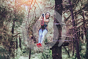 Happy school girl enjoying activity in a climbing adventure park