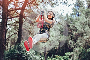 Happy school girl enjoying activity in a climbing adventure park