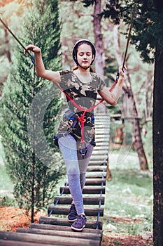 Happy school girl enjoying activity in a climbing adventure park