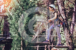 Happy school girl enjoying activity in a climbing adventure park