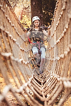 Happy school girl enjoying activity in a climbing adventure park