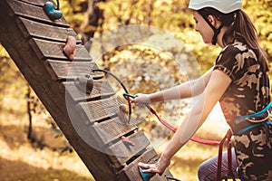 Happy school girl enjoying activity in a climbing adventure park