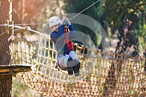 Happy school girl enjoying activity in a climbing adventure park