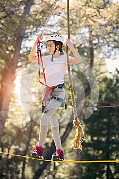 Happy school girl enjoying activity in a climbing adventure park