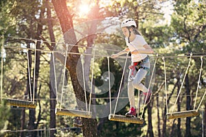 Happy school girl enjoying activity in a climbing adventure park