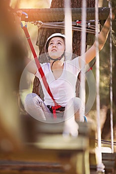 Happy school girl enjoying activity in a climbing adventure park