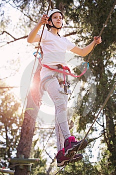 Happy school girl enjoying activity in a climbing adventure park