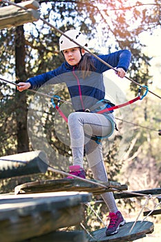 Happy school girl enjoying activity in a climbing adventure park