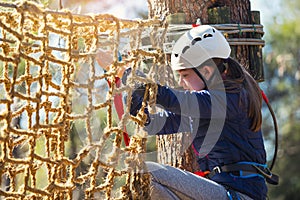 Happy school girl enjoying activity in a climbing adventure park