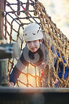 Happy school girl enjoying activity in a climbing adventure park