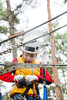 Happy school girl enjoying activity in mountain climbing adventure Park on a spring day