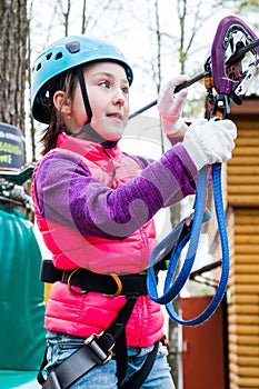 Happy school girl enjoying activity in mountain climbing adventure Park on a spring day