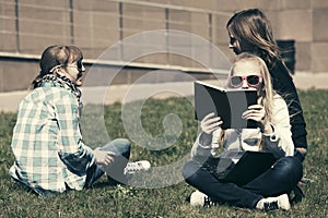 Happy school girls sitting on grass in campus