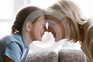 Happy school granddaughter and mature older grandmother touching foreheads.