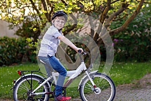 Happy school kid boy having fun with riding of bicycle. Active child with safety helmet making sports with bike in