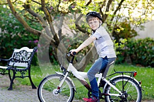 Happy school kid boy having fun with riding of bicycle. Active healthy child with safety helmet making sports with bike
