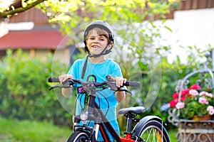 Happy school kid boy having fun with riding of bicycle. Active healthy child with safety helmet making sports with bike