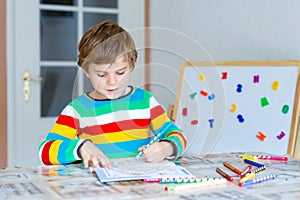 Happy school kid boy at home making homework