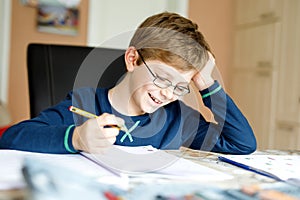 Happy school kid boy at home making homework