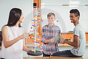 Happy school kids experimenting molecule model in laboratory