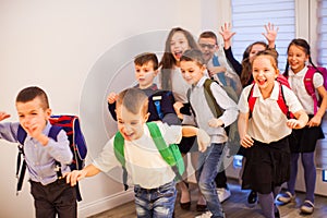 Happy school kids running in elementary school hallway, front view