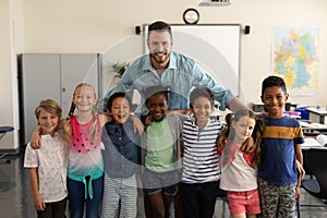 Happy school kids and teacher standing classroom